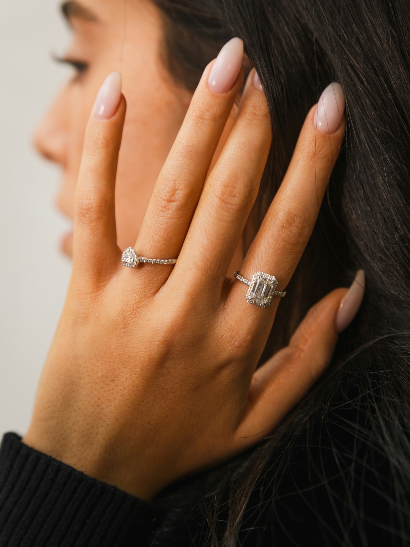 Hand wearing pear and emerald engagement rings