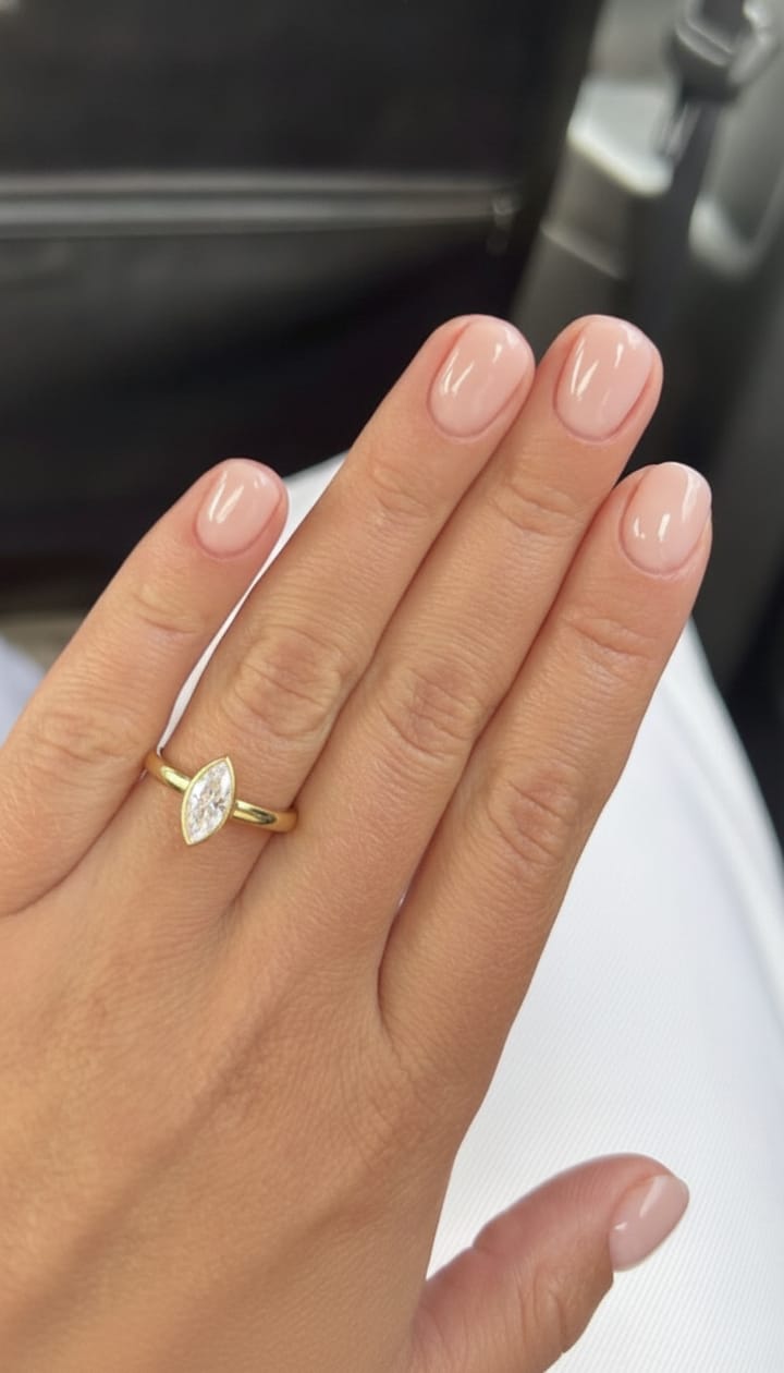 Marquise bezel engagement ring in yellow gold shown on a hand