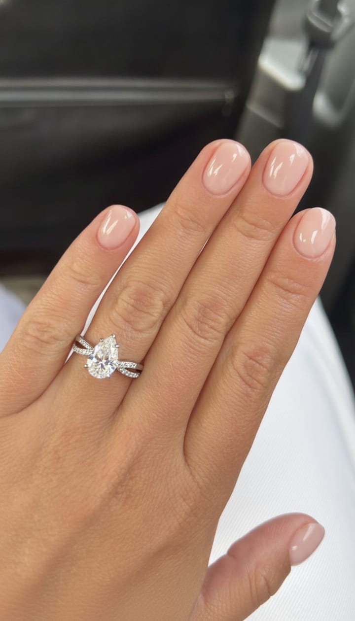 Pear engagement ring on a twist pavé band shown on a hand
